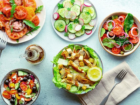Fresh salads, overhead flat lay shot of an assortment. Variety of plates and bowls with green vegetables. Healthy food, top shot, with olive oil